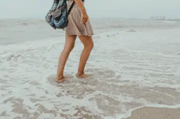 Woman walking on the beach to stop living in the past.