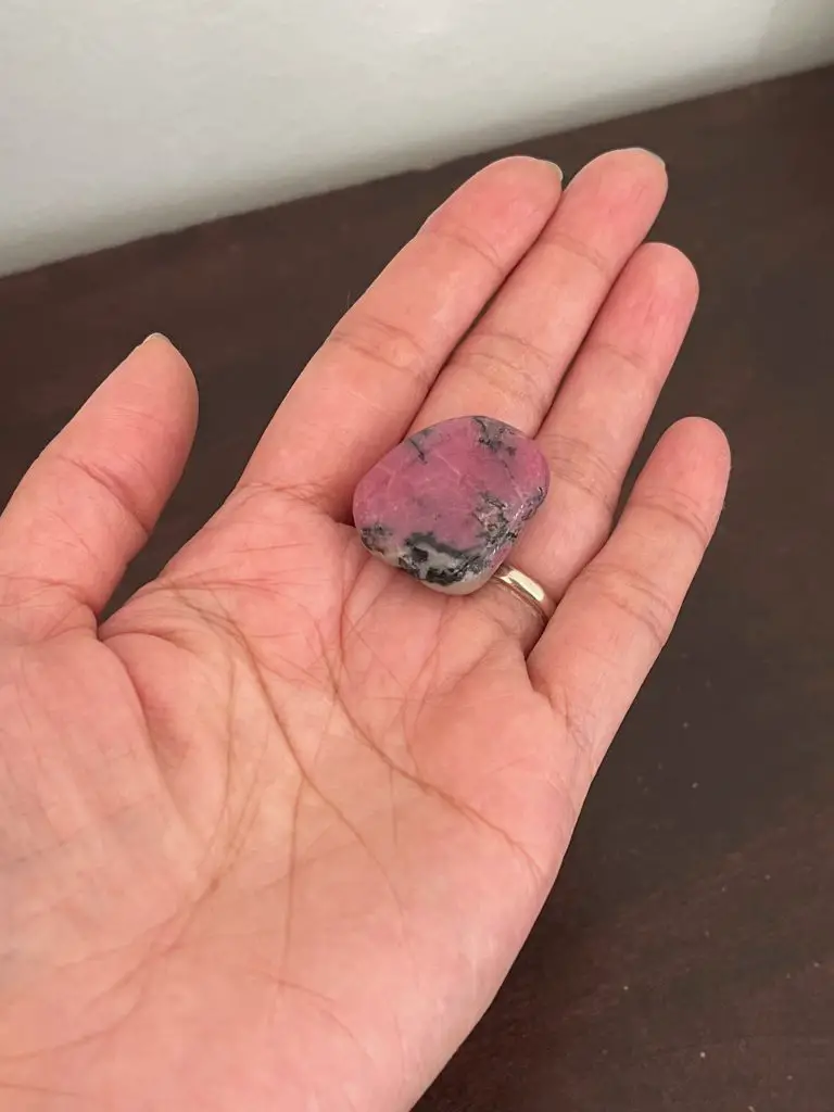 Holding a rhodonite crystal for manifesting.