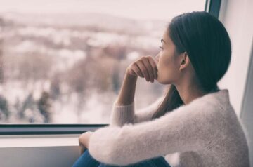 Woman looking at window thinking, "I don't know myself."