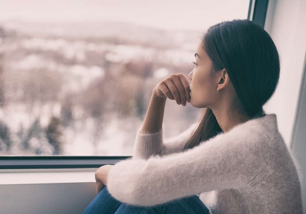 Woman looking at window thinking, "I don't know myself."