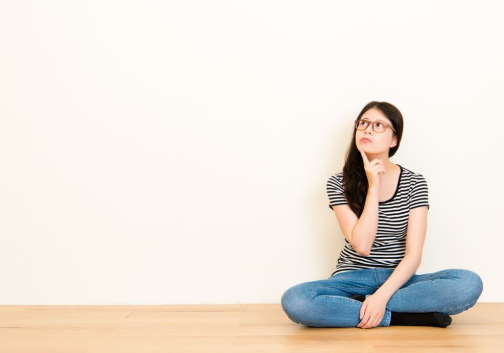 Young woman sitting on the floor contemplating her core beliefs.