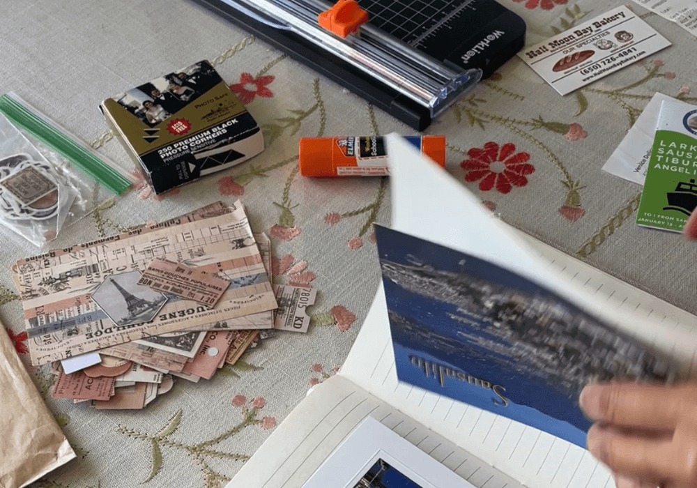 Journal tools sitting on a table: paper, cutter, postcards, etc.