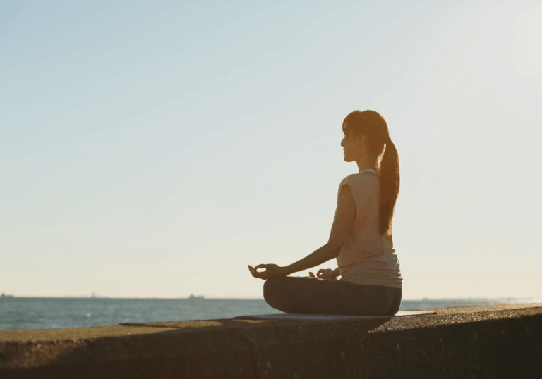 Woman meditating at sunset with light and shadow.